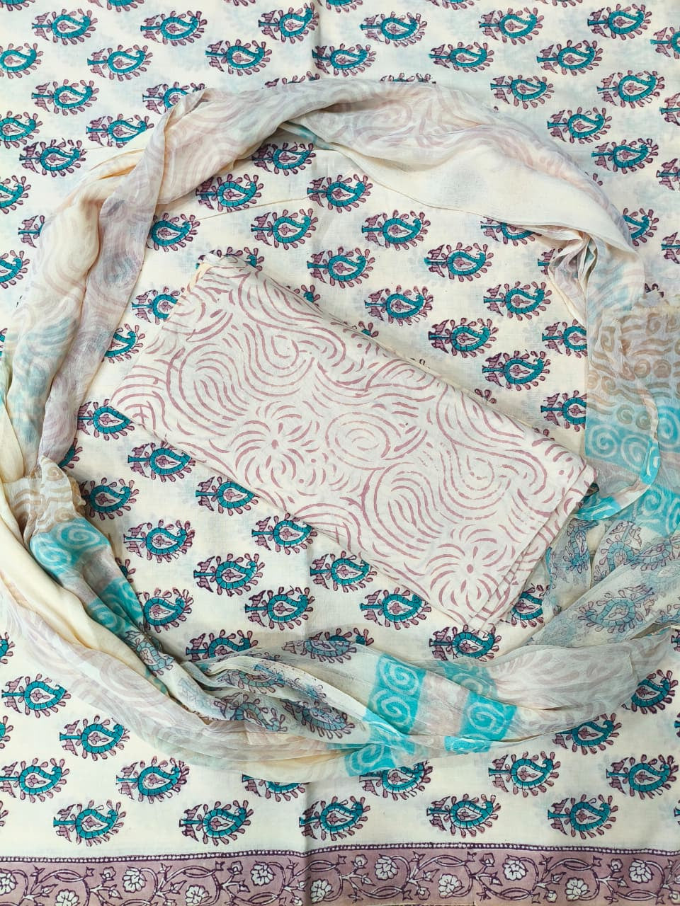 Textile with intricate patterns in white, blue, and purple on a matching fabric background.
